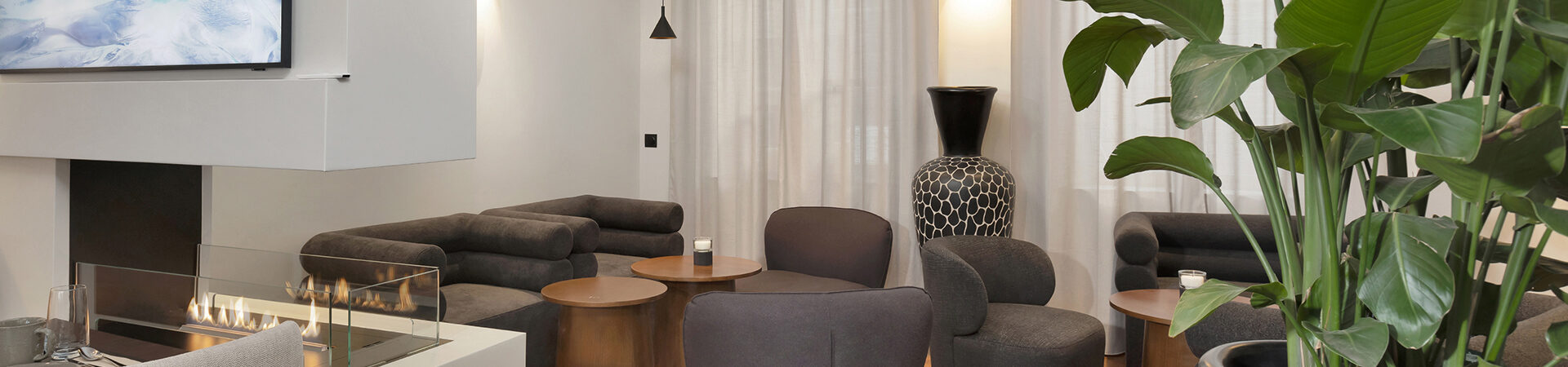 Ambiance cosy autour de la cheminée entre bar et restaurant à l’Hôtel Les Coulisses du Théâtre à Saint-Quentin, lieu idéal pour se détendre