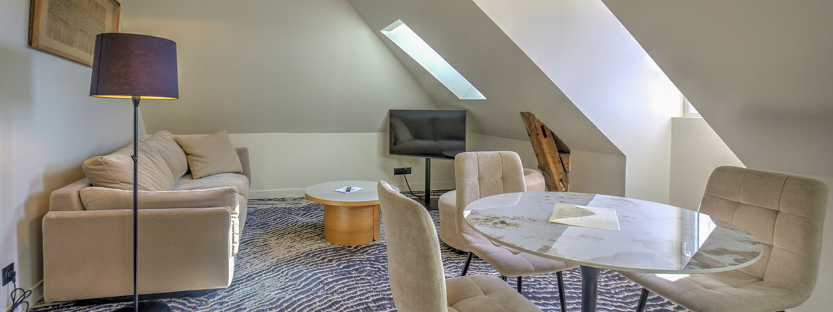 Spacious living room with sofa and fully equipped kitchen in a hotel apartment in Saint-Quentin