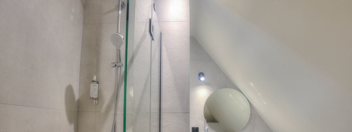 Salle de bain moderne avec baignoire-douche dans studio hôtel